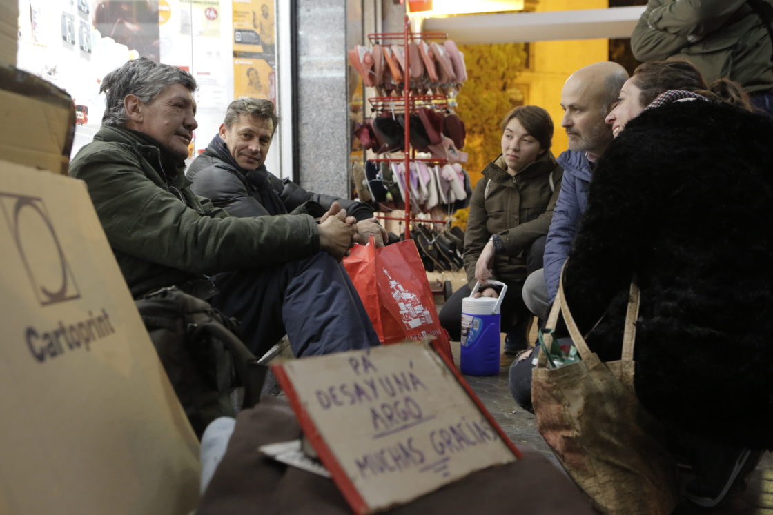 Un grupo de voluntarios conversa con personas sin hogar.
