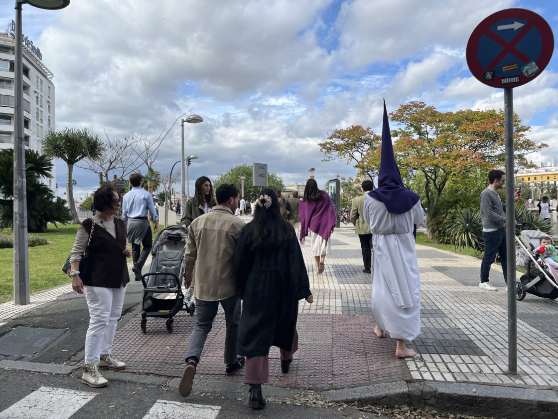 Un nazareno camina descalzo entre la gente, este Lunes Santo en Sevilla. O. C.